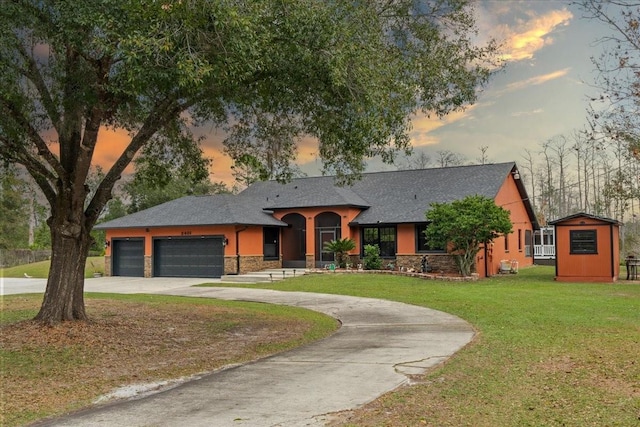 view of front of house with a garage, stone siding, a lawn, and concrete driveway