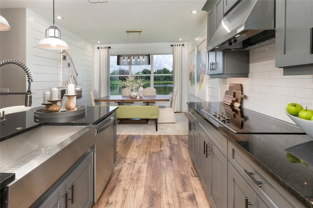 kitchen featuring range hood, dishwasher, pendant lighting, light hardwood / wood-style floors, and gray cabinetry