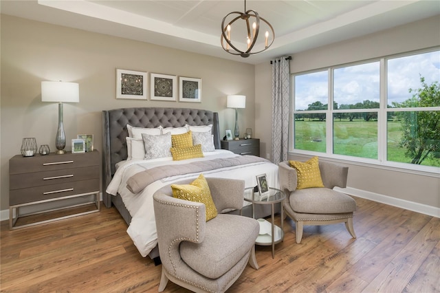 bedroom featuring multiple windows, an inviting chandelier, and hardwood / wood-style floors