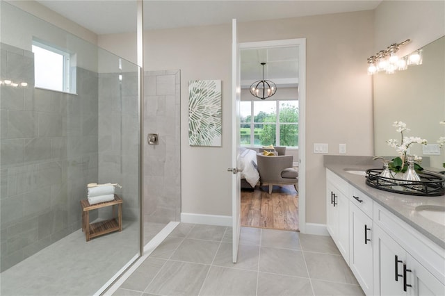 bathroom featuring tile patterned flooring, tiled shower, and vanity