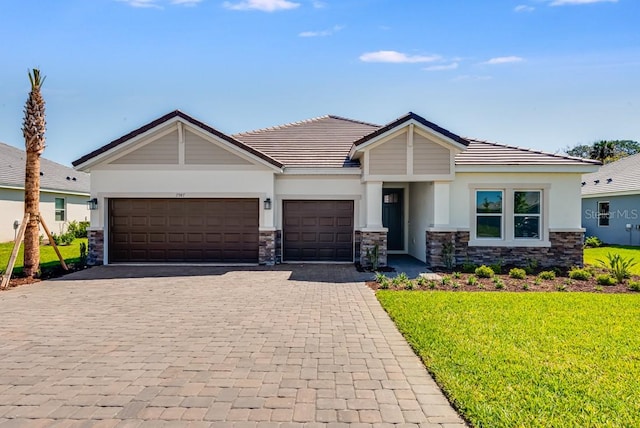 craftsman house featuring stone siding, a front lawn, a garage, and decorative driveway