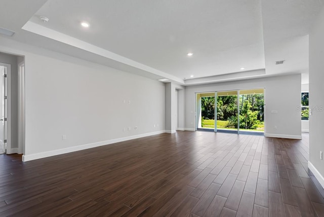 unfurnished living room with recessed lighting, a raised ceiling, baseboards, and dark wood-style floors