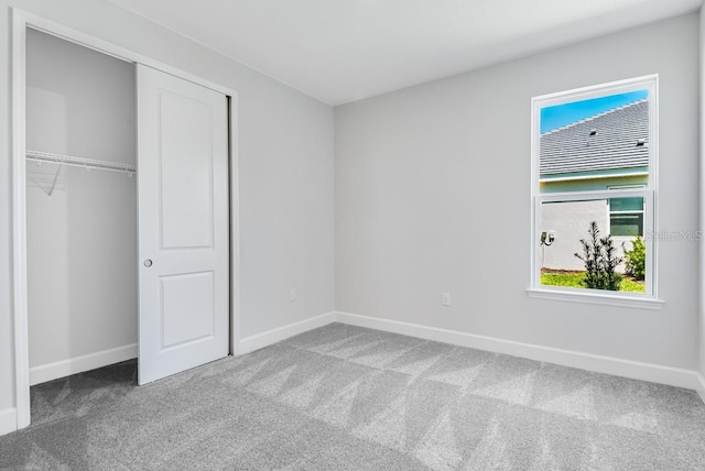 unfurnished bedroom with baseboards, multiple windows, and carpet