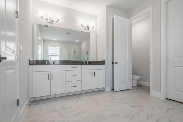 full bathroom featuring a sink, double vanity, toilet, a stall shower, and baseboards