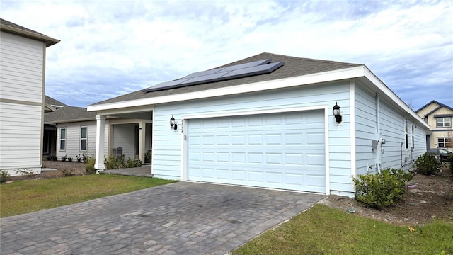 view of front of property featuring a front yard, solar panels, and a garage