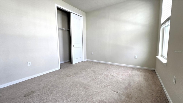 unfurnished bedroom featuring light carpet, a closet, and multiple windows