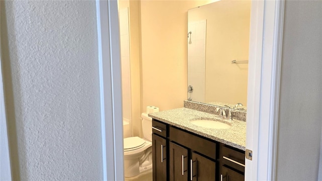 bathroom featuring toilet, vanity, and walk in shower