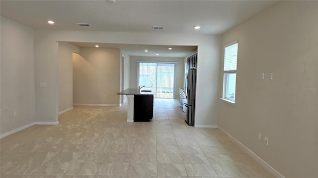 kitchen with a center island with sink, a breakfast bar area, and stainless steel refrigerator