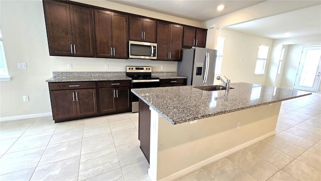 kitchen with light stone counters, sink, appliances with stainless steel finishes, and dark brown cabinets