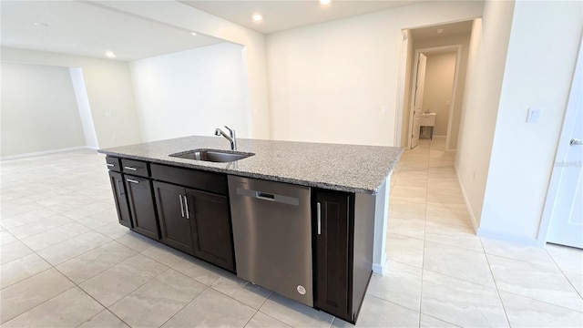 kitchen with stainless steel dishwasher, sink, an island with sink, light tile patterned floors, and light stone counters