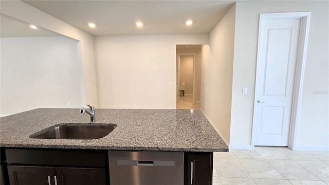 kitchen with light stone countertops, dishwasher, an island with sink, sink, and light tile patterned floors