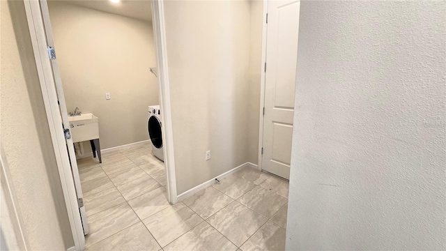 washroom with light tile patterned flooring, washer / clothes dryer, and sink