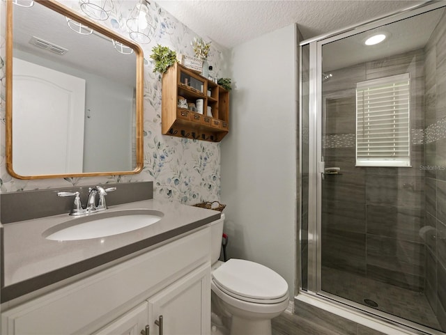 bathroom with toilet, a textured ceiling, a shower with door, and vanity