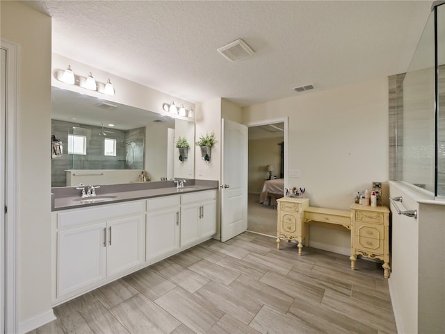 bathroom with a textured ceiling, walk in shower, and vanity