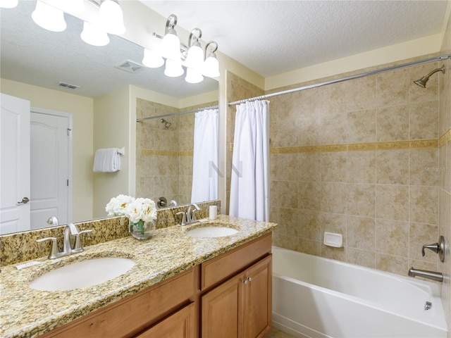 bathroom with shower / bath combo with shower curtain, a textured ceiling, and vanity