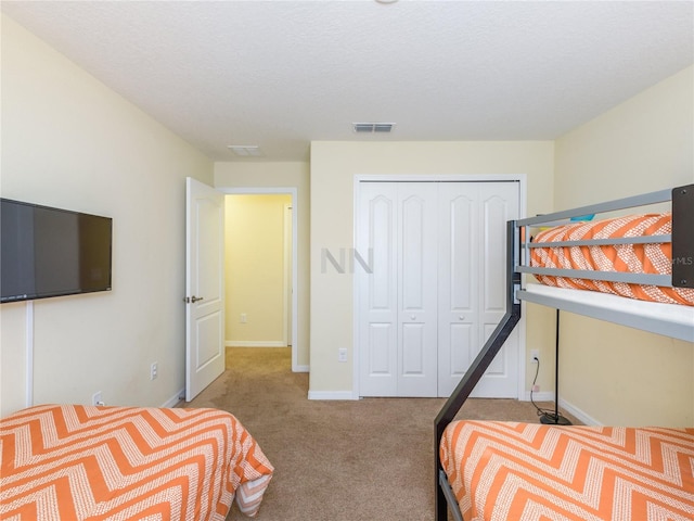 carpeted bedroom with a textured ceiling and a closet