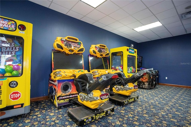 playroom with a paneled ceiling and dark carpet