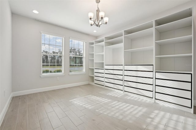 spacious closet featuring a chandelier and light hardwood / wood-style floors