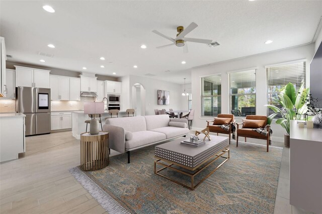 living room featuring light wood-type flooring, ceiling fan, and sink