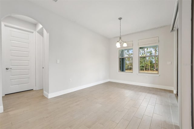 empty room with light hardwood / wood-style flooring and a notable chandelier