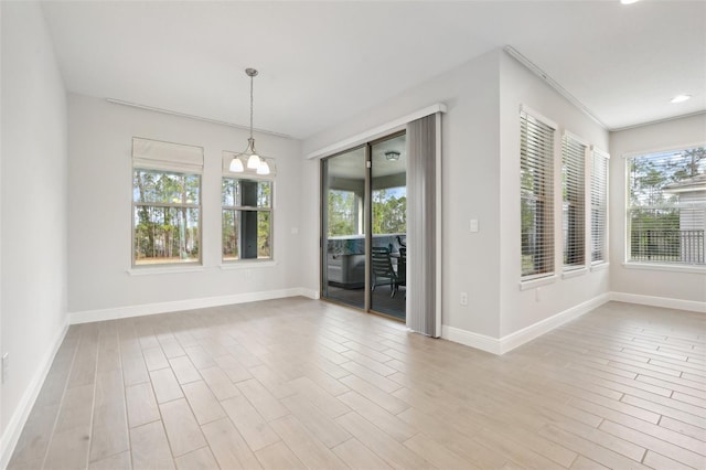 unfurnished room with a notable chandelier and light hardwood / wood-style flooring