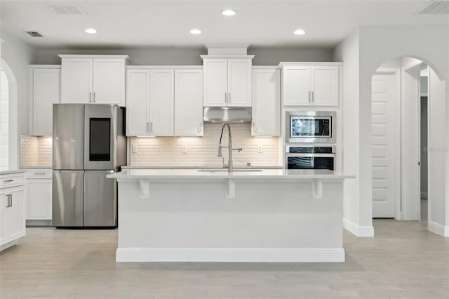 kitchen featuring white cabinetry, an island with sink, a breakfast bar area, appliances with stainless steel finishes, and sink