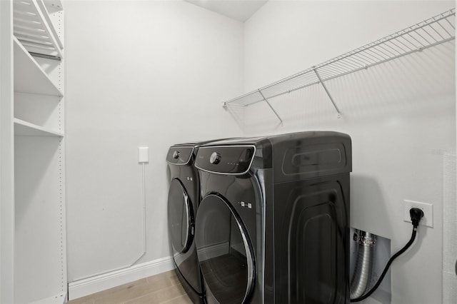 washroom with washer and clothes dryer and light wood-type flooring