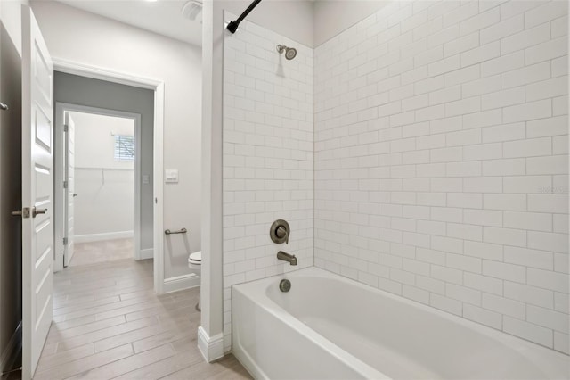 bathroom with toilet and tiled shower / bath