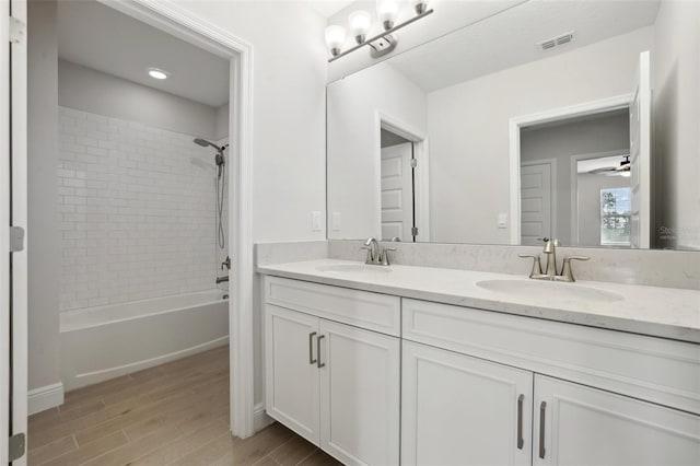 bathroom featuring tiled shower / bath and vanity