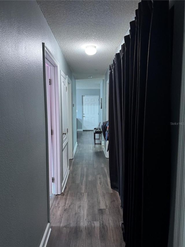 hallway with a textured ceiling and dark hardwood / wood-style floors