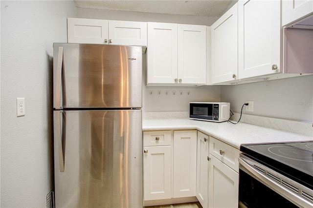 kitchen featuring white cabinetry, range with electric stovetop, and stainless steel refrigerator