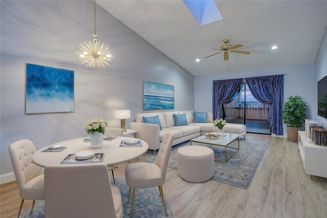 living room with light hardwood / wood-style floors, a textured ceiling, lofted ceiling, and ceiling fan with notable chandelier