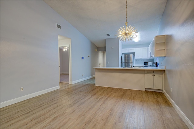 kitchen featuring light hardwood / wood-style floors, pendant lighting, kitchen peninsula, white cabinetry, and stainless steel fridge