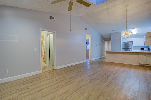 unfurnished living room featuring ceiling fan, light wood-type flooring, vaulted ceiling, and a textured ceiling