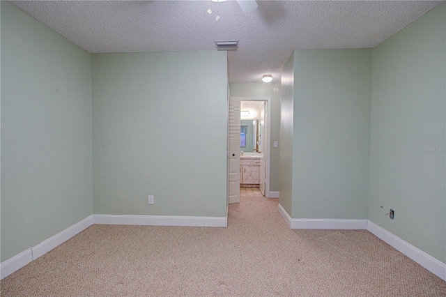 carpeted empty room featuring ceiling fan and a textured ceiling