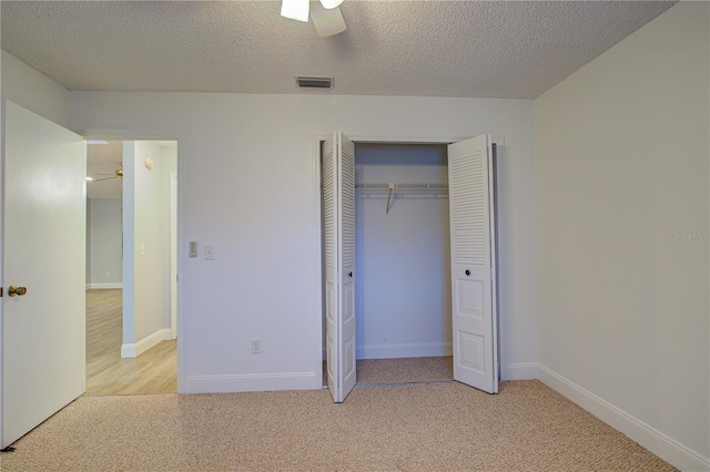 unfurnished bedroom with ceiling fan, light colored carpet, a textured ceiling, and a closet