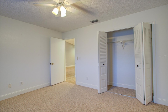 unfurnished bedroom with ceiling fan, a textured ceiling, a closet, and light carpet