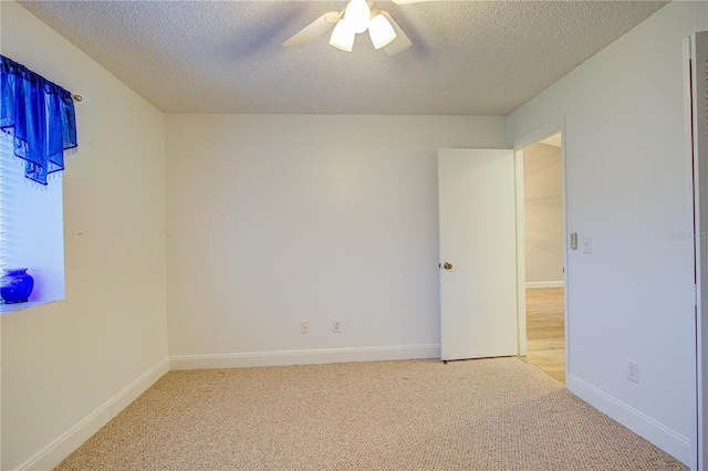 empty room featuring ceiling fan, light colored carpet, and a textured ceiling