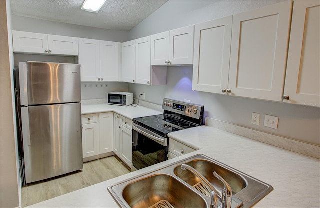 kitchen with white cabinetry, appliances with stainless steel finishes, a textured ceiling, light hardwood / wood-style flooring, and sink