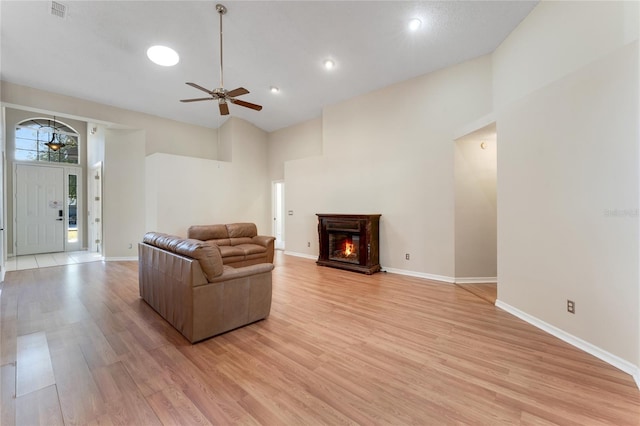 living room featuring light hardwood / wood-style floors, ceiling fan, and a towering ceiling