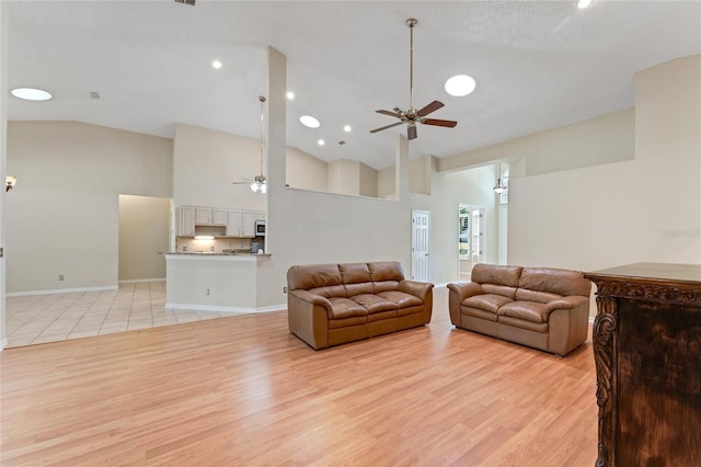 living room featuring high vaulted ceiling, ceiling fan, and light hardwood / wood-style flooring