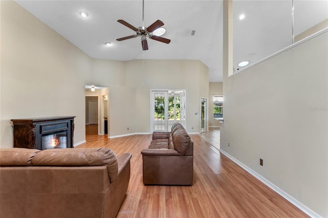 living room featuring light hardwood / wood-style floors, ceiling fan, and high vaulted ceiling