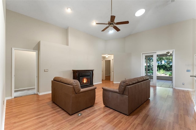 living room with a towering ceiling, ceiling fan, and light hardwood / wood-style flooring