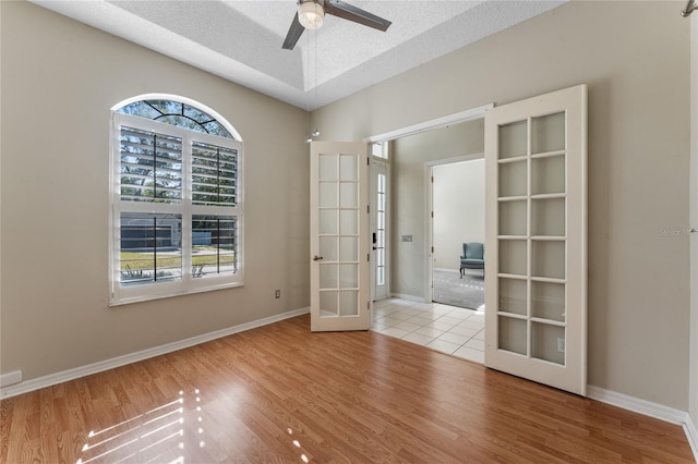 unfurnished room with a textured ceiling, ceiling fan, french doors, and light hardwood / wood-style flooring