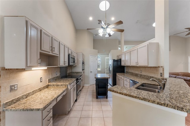 kitchen with appliances with stainless steel finishes, kitchen peninsula, ceiling fan, sink, and tasteful backsplash