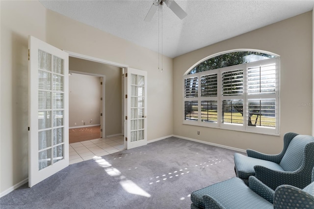 sitting room with light colored carpet, french doors, ceiling fan, and a textured ceiling