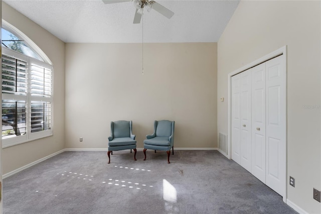 living area with ceiling fan, a textured ceiling, and carpet flooring