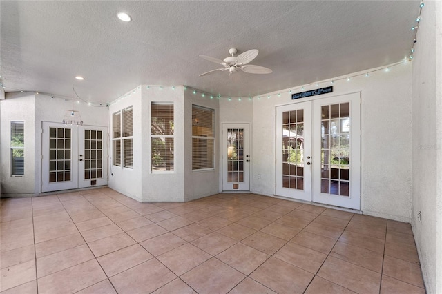 unfurnished sunroom featuring ceiling fan and french doors