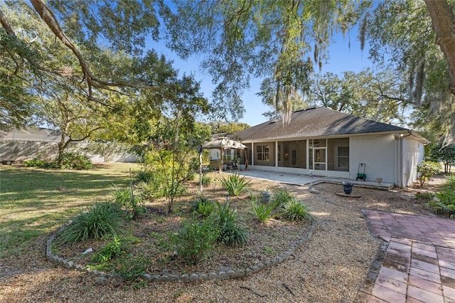 rear view of property featuring a yard, a sunroom, and a patio