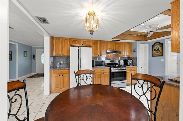 kitchen featuring ceiling fan with notable chandelier, stainless steel appliances, light tile patterned floors, and decorative backsplash